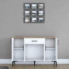 White sideboard with wooden top against a gray wall with framed pictures.