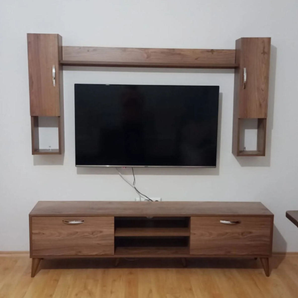 Wooden entertainment center with a TV mounted on a white wall.