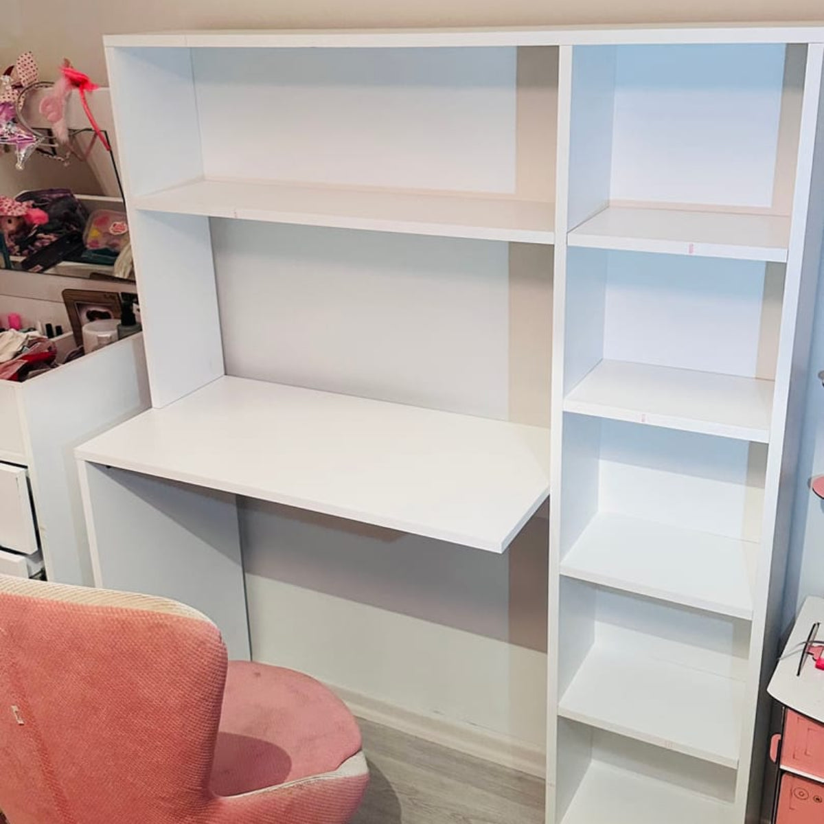 White desk with bookshelf and pink chair in a room setting