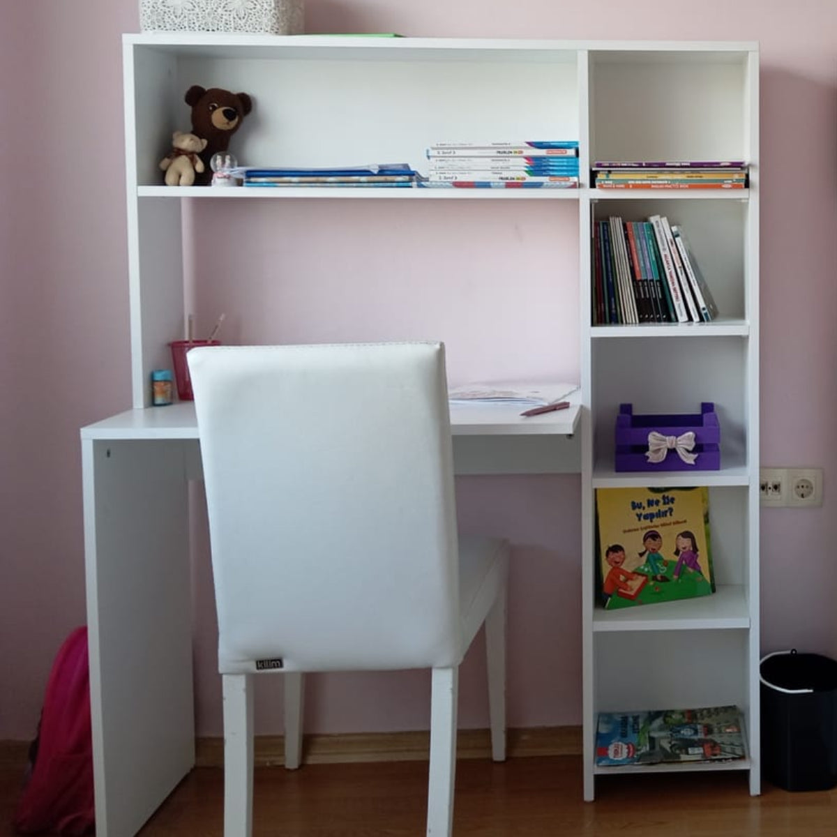 White desk with chair and bookshelf against a pink wall