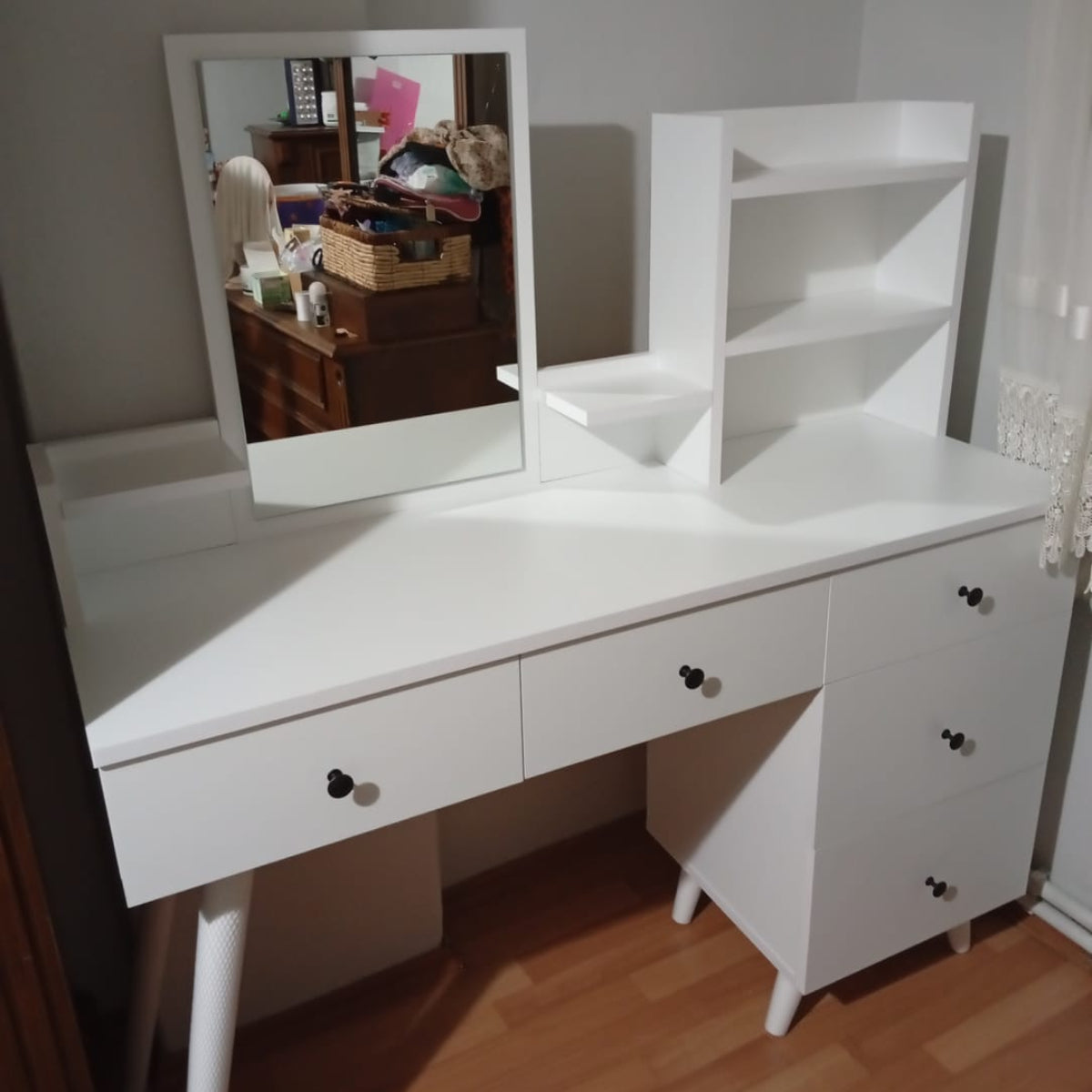 White vanity with mirror on a wooden floor