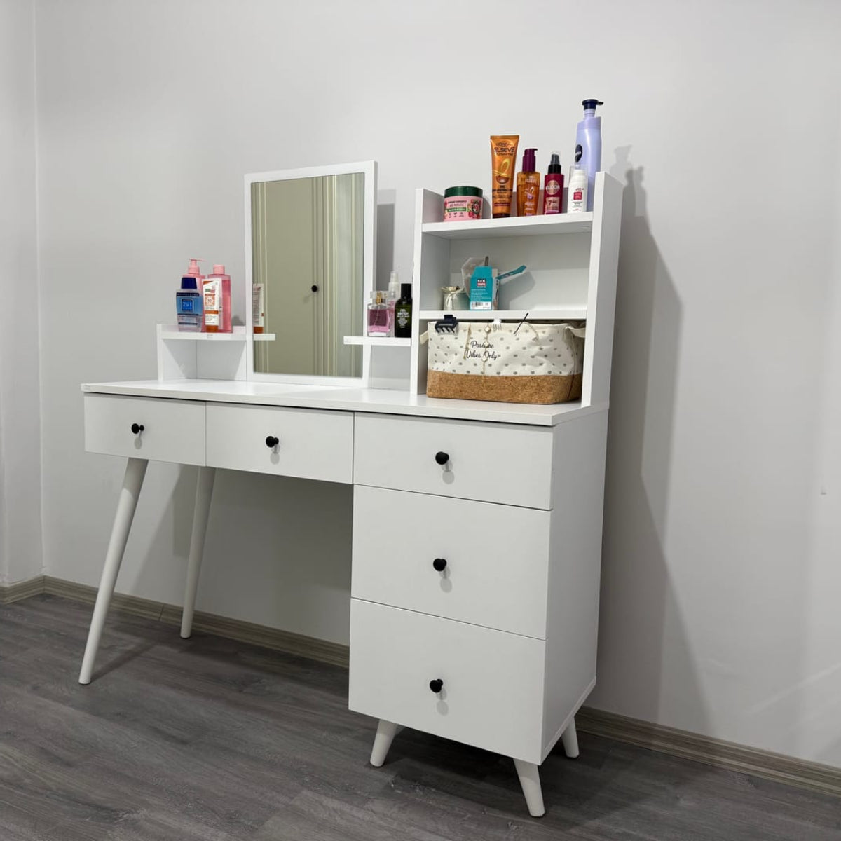 White vanity table with mirror and drawers in a room setting