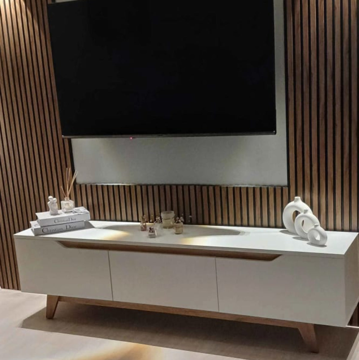 Modern living room with a television mounted on a wooden slat wall.