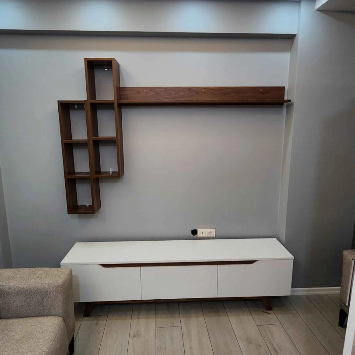 Modern living room with a white entertainment console, wooden shelves, and gray walls.