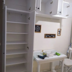 White kitchen with open cabinets revealing a small table and chairs.