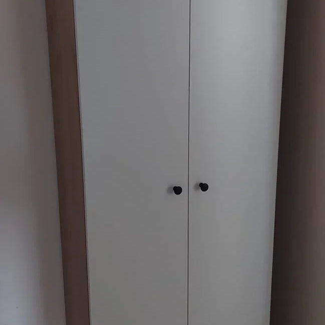 White wardrobe with wooden base and top corner in a room.