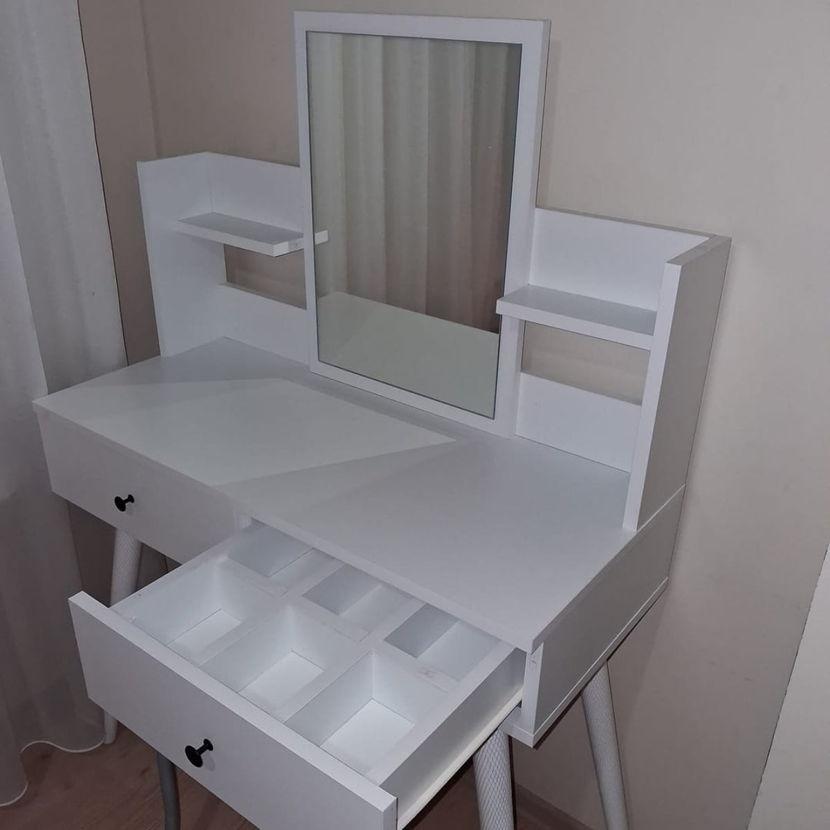 White vanity table with mirror and open drawer in a room.