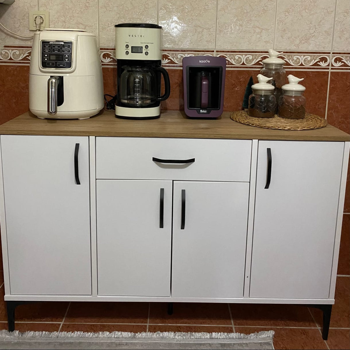 Kitchen counter with coffee maker, toaster, and cabinets against a tiled wall.