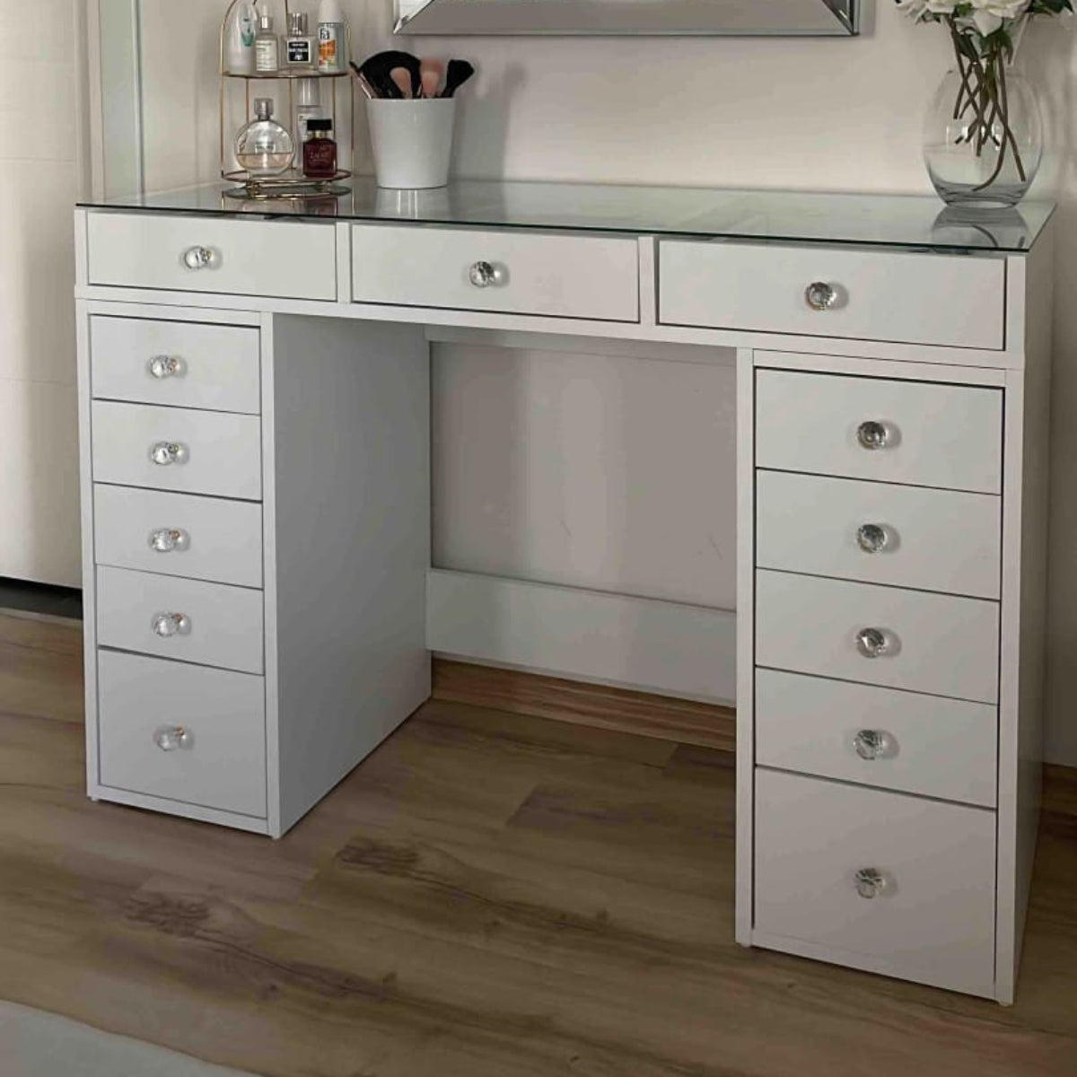 White vanity desk with multiple drawers and a large mirror in a room.