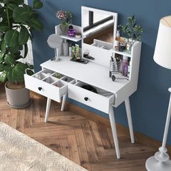 White vanity table with mirror and drawers in a room with a blue wall and wooden floor.