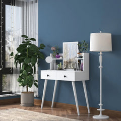 White vanity table with mirror, lamp, and plant against a blue wall.