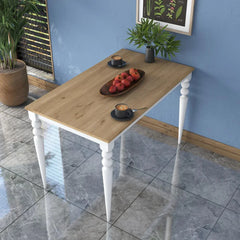 Wooden table with white legs against a blue wall, featuring a plant and decorative items.