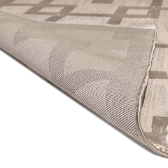 Close-up of a textured beige and brown patterned rug corner.