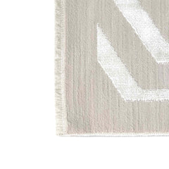 Close-up of a textured rug with a white leaf design on a light gray background