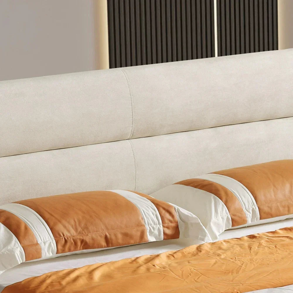 Close-up of a bed with beige and brown bedding against a neutral wall.