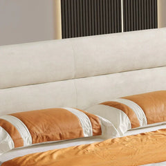 Close-up of a bed with beige and brown bedding against a neutral wall.