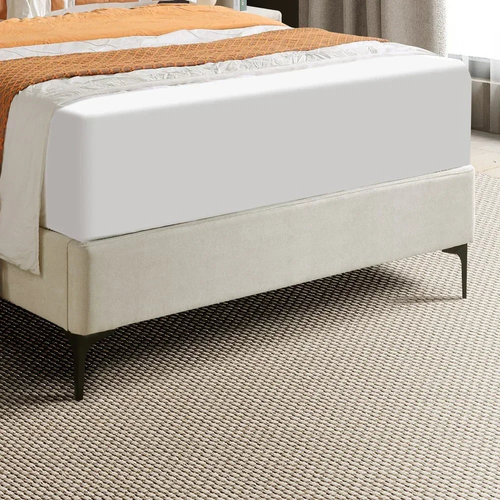Bed with white mattress and orange blanket on a textured floor