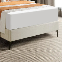 Bed with white mattress and orange blanket on a textured floor