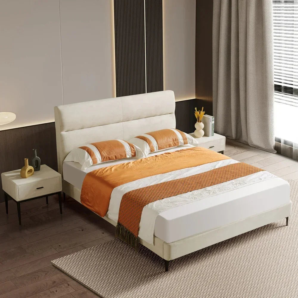 Modern bedroom with a bed featuring orange and white bedding, nightstands, and decor.