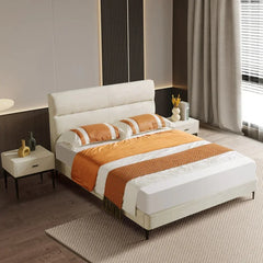 Modern bedroom with a bed featuring orange and white bedding, nightstands, and decor.