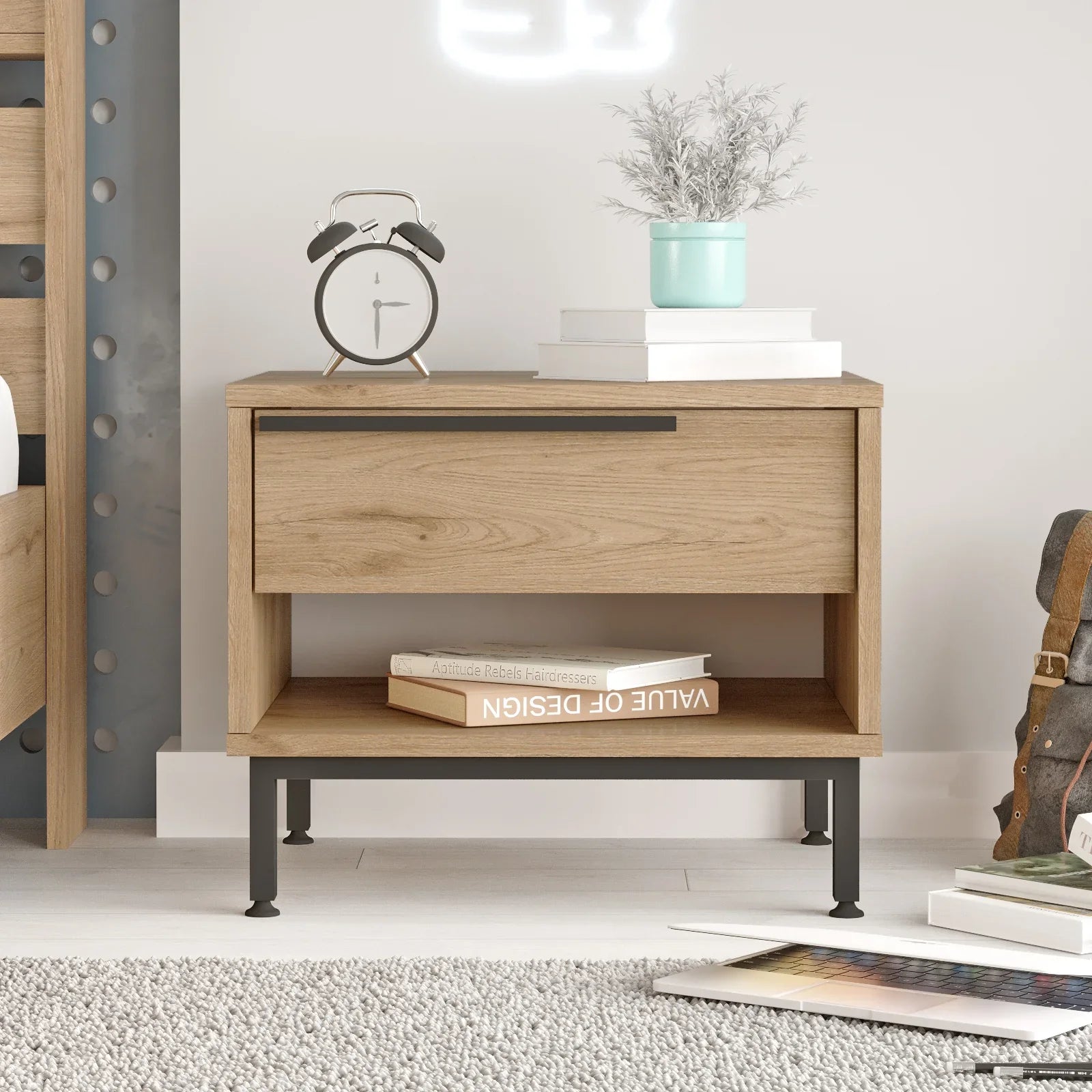 Wooden nightstand with books, alarm clock, and plant in a modern bedroom setting.