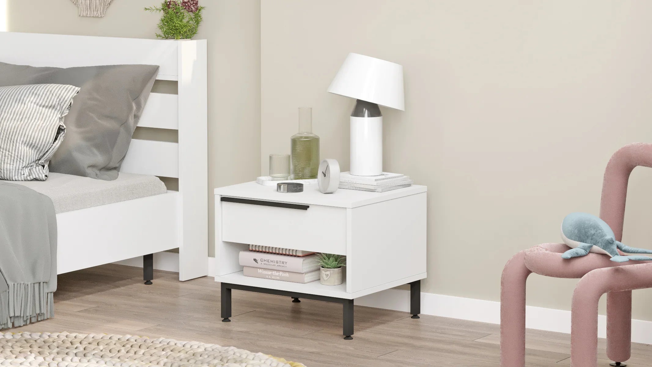 White nightstand with lamp and decor items next to a bed in a bedroom.
