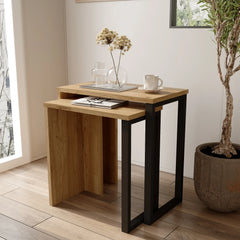 Small wooden desk with black metal legs in a room with a plant and window.
