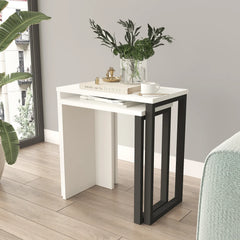 White and black side table with decorative items in a room with a plant and window.