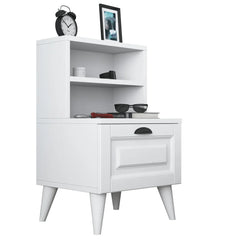 White nightstand with a shelf and drawer, featuring decorative items on top.