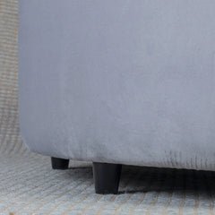 Close-up of a gray upholstered chair with wooden legs on a textured surface.