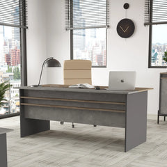 Modern office desk with chair and laptop in a bright room with large windows.
