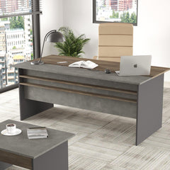 Modern office desk with a laptop, books, and a lamp in a bright room with large windows.